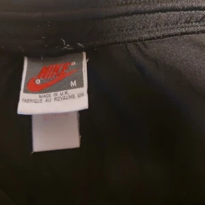 Svarta träningsshorts från Nike - Säljer ett par svarta träningsshorts från Nike i storlek M. De är perfekta för gymmet eller löprundan. Shortsen har en enkel design med Nike-loggan på benet. De är bekväma och har en normal passform.
