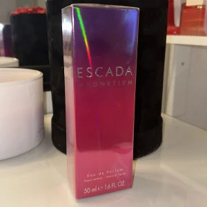Escada Magnetism Eau de Parfum - Säljer(oöppnad)en lyxig och förförisk parfym från Escada, Magnetism. Flaskan är elegant och har en djup rosa färg med en modern, geometrisk form. Perfekt för den som vill ha en doft som sticker ut och lämnar ett bestående intryck. Flaskan innehåller 50 ml(edp) av denna underbara doft. 