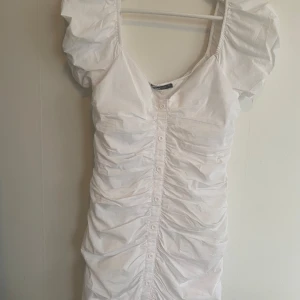 Vit klänning L - Vit kort draperad sommarklänning från Gina, storlek 40/L (passar M enligt mig) Fina dekorativa knappar framtill.