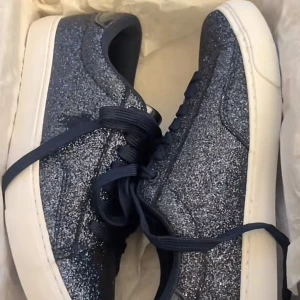 Glittriga sneakers från Polo Ralph Lauren - Säljer ett par snygga glittriga sneakers från Polo Ralph Lauren. Skorna är i en mörkblå färg med en vit sula och har snörning framtill. Perfekta för att ge din outfit lite extra bling!