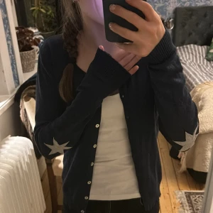 Mörkblå kofta med stjärndetaljer från Culture - Säljer en snygg mörkblå kofta från Culture med vita stjärnor på ärmarna. Koftan har knappar framtill och långa ärmar. Bra skick men är välanvänd! Köptes på Zalando för 450kr säljer för 200kr! Pris kan diskuteras🥰