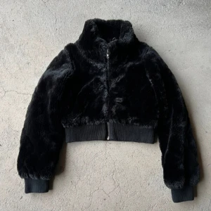 Vintage pälsjacka från ONLY - Vintage svart pälsjacka från ONLY med dragkedja framtill. Jackan har långa ärmar och ribbade muddar vid ärmslut och nederkant. Perfekt för kyliga dagar när du vill hålla dig varm och stilren! 🎀 
