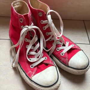 Röda Converse - Säljer ett par klassiska röda Converse med vita snören. Skorna har en hög modell med det ikoniska märket på sidan. —————————  Använt skick - slitage i hälen men bättre skick än de andra jag säljer.