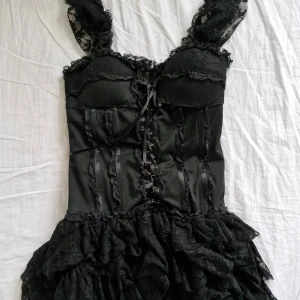 Gotisk klänning med spets - Säljer denna fantastiska goth-klänning från Sonic London 🖤🖤 Svart modell med kort volangkjol och inbyggd bustier. Storlek 12 (L) men passar även M. Normala bruksspår (se bilder) men inga anmärkningsvärda defekter!                                Pris är självklart förhandlingsbart 💕