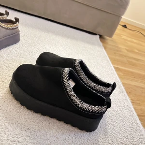 Svarta slip-on skor med mönstrad kant 39 - Snygga svarta slip-on skor med en dekorativ mönstrad kant i vitt. Skorna har en tjock sula och är perfekta för en avslappnad stil. HELT nya, aldrig använda! Storlek 39