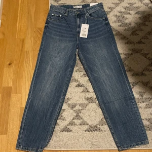 Blå jeans från Bershka - Säljer ett par snygga blå jeans från Bershka i 90-talsstil. De har en wide fit och är midwaist. Jeansen är oanvända med lapparna kvar. 