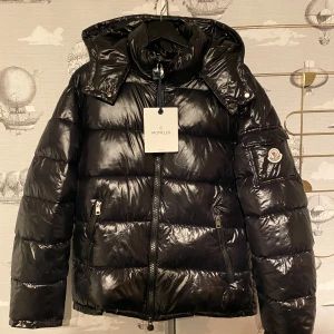 Moncler Maya - snygg svart pufferjacka från Moncler. Jackan har en glansig finish med dragkedja och långa ärmar. Den är perfekt för kalla dagar och har en klassisk Moncler-logga på ärmen. Storlek: 2/M, Finns inte din storlek? Vi kan fixa alla storlekar bara att höra av sig så löser vi de du vill ha! Vi kan även fixa alla skor, tröjor, jackor, västar osv till riktigt bra pris bara att skicka bild på vad du söker och storlek så ska vi göra de vi kan!/// Es Clothing  MONCLER CARDIGANS KOMMER IN  5-12 FEB!