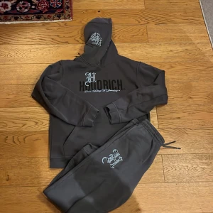 Grå hoodie från Hoodrich - Säljer en grå hoodie från Hoodrich med tryck på bröstet och en mönstrad insida av huvan. Perfekt för en avslappnad stil. Hoodien har långa ärmar och en klassisk passform.