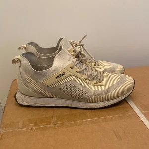 Hugo boss skor-sneakers - Snygga beige sneakers från Hugo med stickad ovandel och snörning. Skorna är riktigt sköna. Lite smutsiga men smutsen går bort efter en tvätt skulle jag tro💫 det finns en liten fläck vid toppen av skon men man märker inte den så mycket ✅