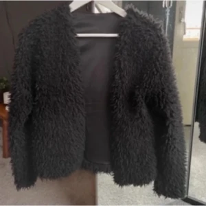 Svart teddyjacka - Mysig svart teddyjacka med långärmad design. Jackan har en fluffig textur som ger en trendig look.