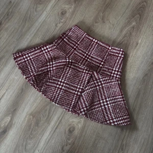 Rutig kjol från NA-KD - Snygg rutig kjol från NA-KD i rött och vitt. Kjolen har en kort längd och en klassisk A-linjeform som ger en fin siluett. Perfekt för att addera lite mönster till din outfit.