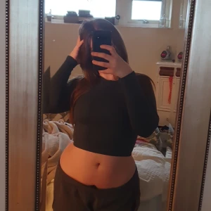 Mörkgrön croppad tröja från MM Sports - Säljer en mörkgrön croppad tröja från MM Sports. Tröjan har långa ärmar och en enkel design med en liten logotyp på bröstet. Perfekt för en sportig look eller avslappnad stil. Passar bra till både jeans och träningsbyxor💚