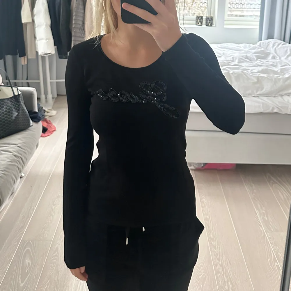 Snygg svart långärmad topp med paljettdetalj framtill. Perfekt för en stilren look. Toppen har en tight passform som framhäver figuren. Märket är Guess. Hittade inte någon storlek då storlekslappen är bortklippt men uppskattar till S. Nypris är 699kr. Neuletakit & Villapaidat.