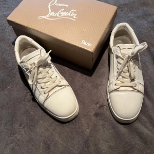 Christian Louboutin  - OBS!!! INTRESSEKOLL!! CHRISTIAN LOUBOUTIN Fun Vieira leather sneakers. Skorna har vita färg med en guldig detalj. Längst bak på skorna skiftar färgen mellan blå/rosa. Köpta på Fashionette i början av 2024.