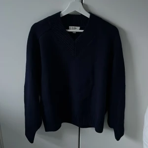 Mörkblå tröja från COS - Säljer en stilren mörkblå tröja från COS. Tröjan har en v-ringad design och långa ärmar. Den är tillverkad i ett mjukt stickat material.