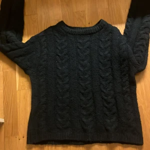 Svart stickad tröja från 157 - Säljer en svart stickad tröja från 157 i storlek XS. Tröjan har ett klassiskt flätmönster och långa ärmar. Perfekt för kyliga dagar. Hör av dig vid intresse!