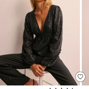 Svart glittrig blus - Snygg svart blus med glittriga detaljer och djup v-ringning. Blusen har långa ärmar och en elegant passform som passar perfekt för festliga tillfällen. Aldrig använd , prislapp kvar. Priset kan alltid diskuteras 