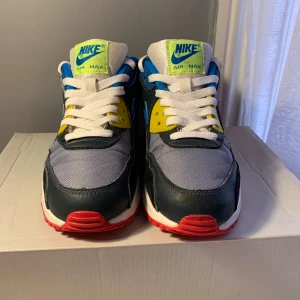 Nike Air Max i färgglad design - Snygga Nike Air Max sneakers med en mix av blå, gul, grå och röd. Skorna har en klassisk Air Max-sula och snörning framtill. Perfekta för dig som vill ha en färgglad och bekväm stil.