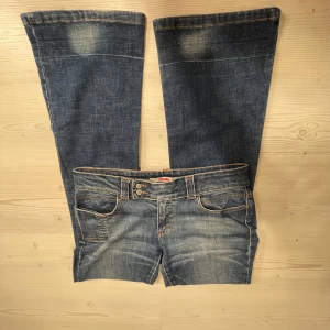 Blå bootcut jeans från only - Snygga blå bootcut jeans från only med låg midja och klassisk femficksdesign. Jeansen har en lätt slitning för en trendig look och dubbla knappar i midjan. Midjemåttet 40, Innerbenslängd 79 och grenmått 19. Jag är 167💗