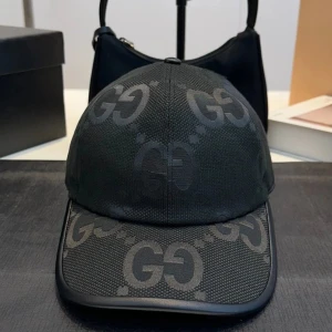 Kepsar med GG-mönster - Snygga kepsar med det ikoniska GG-mönstret. Finns i svart och beige med gröna och röda detaljer på sidan. Perfekt för att ge din outfit en lyxig touch.
