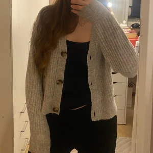 Grå ribbad kofta - Säljer en mysig grå ribbad kofta med stora knappar framtill. Från H&M