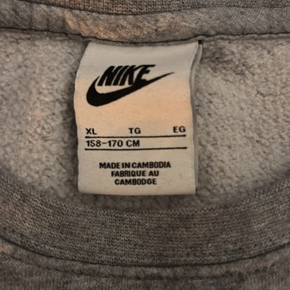 Säljer en grå tröja från Nike med långärmad design och klassisk Nike-logga på bröstet. . Hupparit & Collegepaidat.
