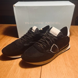 Svarta Philippe Model runners - Snygga svarta sneakers från Philippe Model med vita detaljer. Skorna har en klassisk design med snörning och en bekväm sula. Perfekta för en stilren look.