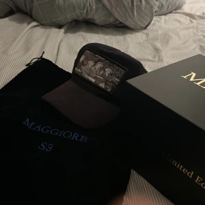 Svart keps från Maggiore - Snygg svart keps från Maggiore med ett unikt tryck framtill. Kepsen har ett nätmaterial på baksidan för bättre ventilation och en justerbar rem för perfekt passform. Perfekt för en cool och avslappnad stil.