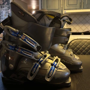 Grå pjäxor från Nordica - Säljer ett par svarta pjäxor från Nordica med justerbar funktion för skidåkning och promenad. De har flera spännen för optimal passform och en flex index på 40 för komfort. Perfekta för vinterns äventyr i backen!