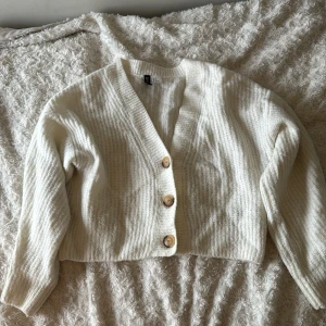 Vit kofta  - En kofta med kortare passform. Det följer även med en extra knapp