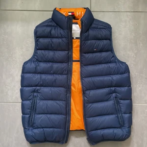 Mörkblå Tommy Hilfiger väst - Mörkblå väst från Tommy Hilfiger, storlek 164. Använd ett fåtal gånger, mycket fint skick. Frakten är inkluderad.