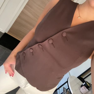 Brun bäst från Nakd  - Snygg väst från Nakd i färgen brun. Helt oanvänd med lapparna kvar, säljer då den inte kommit till användning. Köptes för 499kr 