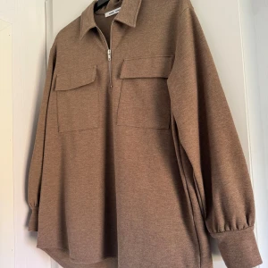 Beige tröja med dragkedja - Säljer en snygg beige tröja från Samsøe Samsøe. Den har en dragkedja framtill och två stora fickor på bröstet. Tröjan har långa ärmar med resår vid ärmsluten. Perfekt för en avslappnad stil!