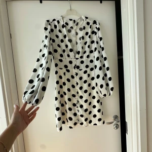 Klänning  - Letar du efter det ultimata statement-plagget för ditt nästa evenemang? Sök inte längre! Vår ärmlösa, rygglösa festklänning utstrålar elegans och sofistikering. Med sin eleganta design och smickrande silhuett är denna klänning perfekt för att göra en