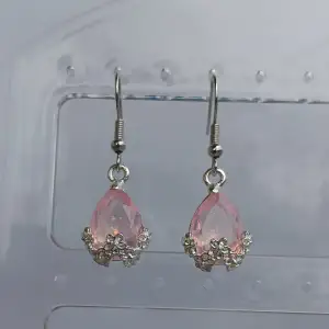 Säljer ett par superfina örhängen med rosa droppformade stenar. De har snygga silverdetaljer som håller fast stenarna och ger en elegant look. Perfekta för att piffa upp vilken outfit som helst! 💖