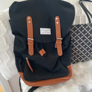 Ryggsäck  - Nästan helt oanvänd ryggsäck från Lager 157. Ryggsäcken är i linnetyg med bruna läderdetaljer. Väskan passar perfekt till jobb eller skola då den är rymlig och har flera fack. Banden är justerbara. Hör av er vid fler frågor!