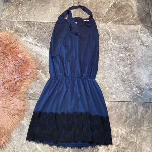 Mörkblå klänning med spetsdetaljer - Säljer en superfin mörkblå nattklänning med spetsdetaljer längst ner. Den har en halterneck-design och är perfekt för att sova i. Klänningen är i nyskick och har en elastisk midja för en bekväm passform.