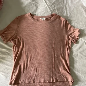 T-shirt från monki - Snygg rosa t-shirt med ribbstickning. T-shirten har en rund halsringning och korta ärmar. Den är i en mjuk och bekväm kvalitet. storlek M