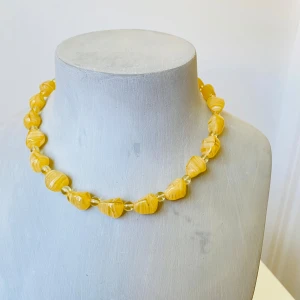 Gult halsband med pärlor - Säljer ett superhärligt gult halsband med stora, oregelbundna glaspärlor. Det har en enkel och stilren design med en metallspänne som gör det lätt att ta på och av. Perfekt för att liva upp vilken outfit som helst!