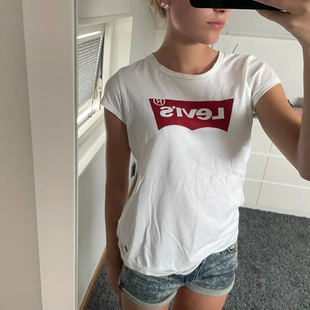 Säljer en snygg vit t-shirt från Levi's med deras klassiska röda logga på bröstet. Perfekt för en casual look och passar till allt! T-shirten är i bra skick och har korta ärmar.. T-shirts.