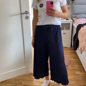 Mörkblå vida byxor med knytband - Säljer ett par mörkblå vida byxor med knytband i midjan. De är superbekväma och har en snygg plisserad design. Noppriga. 