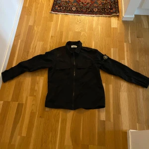 Stone island overshirt - Säljer nu min Stone island overshirt i strl M som jag använt ett tag runt 4-5 månader. Liten defekt uppe vid högra axeln men går att ta bort förmodligen. Ganska tunt material, alltså inte som en vanlig overshirt. Oklarhet på om den är äkta eller inte