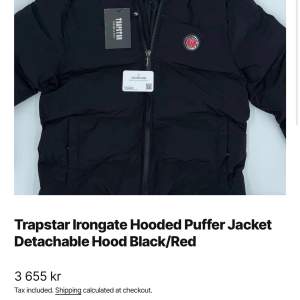 Säljer en snygg och varm pufferjacka från Trapstar med avtagbar huva. Jackan är svart med röda detaljer och har en cool Trapstar-logga på ryggen. Den är tillverkad i 100% polyester vilket gör den både lätt och bekväm. Perfekt för kalla dagar!