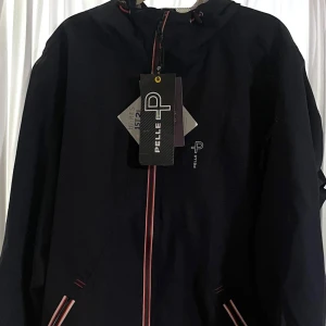 Regnjacka seglarjacka Pelle p - Windproof, rainproof, breathable  Vindjacka regnjacka seglarjacka. Finns i M/L/XL, beställt och glömt skicka tillbaka därav låga priset.  Den har meshfoder och justerbar fast huva. Fickorna har vattentäta dragkedjor. Ordinarie pris 2800kr.