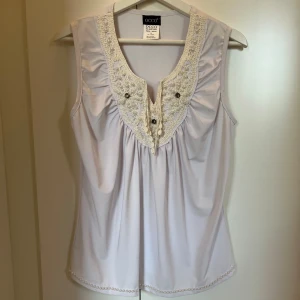 Vit linne med virkade detaljer - Jättefint vit linne med virkade detaljer på bröstet och små pärlor vid bröst och nedre kant.🤍