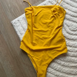 Baddräkt  - Gul baddräkt från H&M. Aldrig använd, plomberad med prislapp kvar.