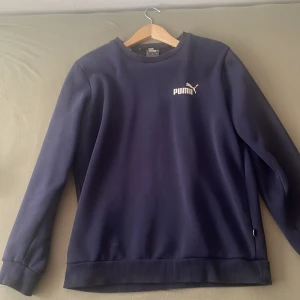 Mörkblå tröja från Puma - Säljer en snygg och bekväm mörkblå tröja från Puma. Den har en klassisk design med rund hals och långa ärmar. Perfekt för både vardag och träning. Tröjan är i bra skick och redo för en ny ägare!
