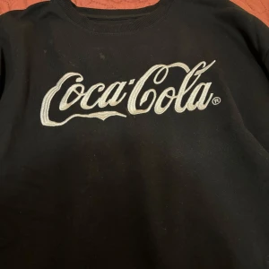 Coca cola hoodie - En coca cola sweetshirt, fick den i present men antagligen köpt från coca cola butiken i gröna Lund! Inga skador på den då den knappt är använd, kommer bara inte till användning men annars är den skön och mysig. (Tvättas innan postningen) 