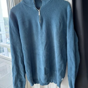 Blå quaterzip - Superfin quaterzip, passar både man och kvinna. Perfekt för att få in lite färg i hösten och vinterns outfits. Mått: Axelbredd 58cm, längd 63cm. 