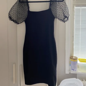 Svart klänning med mesh - Svart figurnära klänning med meshdetalj. Normalt skick. Stl: 36